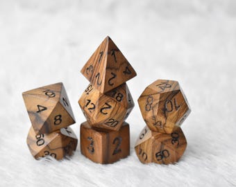 May include: A set of wooden polyhedral dice, perfect for tabletop games. The dice are a warm brown color with visible wood grain and black numbering. The set includes various shapes, such as a cube, pyramid, and a 20-sided die.