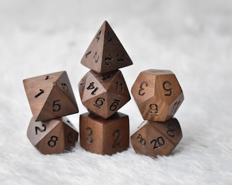 May include: A collection of seven wooden dice in various geometric shapes, including a pyramid, cube, and dodecahedron. The dice are a rich brown color with engraved numbers, perfect for tabletop games.