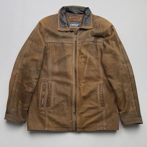 Pu&ograve; includere: Una giacca in pelle marrone con finitura vissuta, dotata di colletto nero, chiusura frontale con zip integrale e due tasche verticali con cerniera sul davanti. L'etichetta interna sul colletto riporta il nome del marchio SWEEP in bianco.