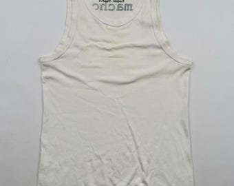 May include: A white vest top with a crew neck. The text "20% muscle, 30% sex, 40% force, 10% self-respect" is printed in black on the upper left side. The word "MAGIC" is printed in black below the text.