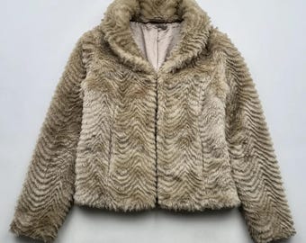 May include: A beige faux fur jacket with a long, pointed collar and a zipper closure.
