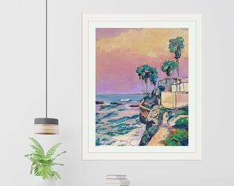 May include: A framed painting of a seascape with palm trees and a cliff. The sky is a vibrant pink and orange, and the ocean is a deep blue. The painting is in a white frame.