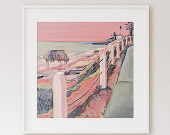 May include: A painting of a pink and blue beach scene with a white picket fence leading to a small hut. The sky is a soft pink and the water is a light blue. The painting is framed in white.