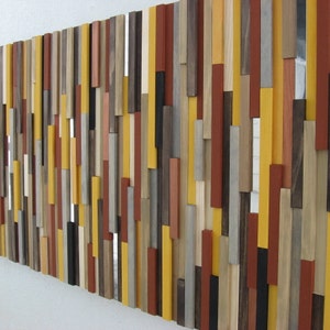 Puede incluir: Una pieza de arte de pared hecha de varias piezas de madera de diferentes colores y tama&ntilde;os. Las piezas de madera est&aacute;n dispuestas en un patr&oacute;n vertical, creando un dise&ntilde;o moderno y abstracto. Los colores incluyen tonos de marr&oacute;n, amarillo, rojo y gris.