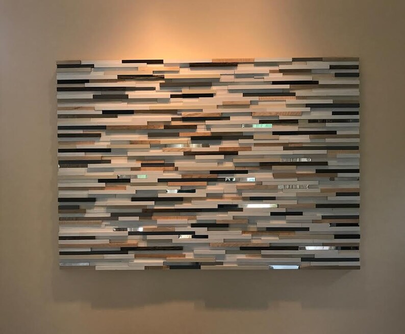 May include: A wall art piece made of wood and mirror tiles. The tiles are arranged in a horizontal pattern, creating a modern and abstract design. The piece is a light brown, white, and black color.
