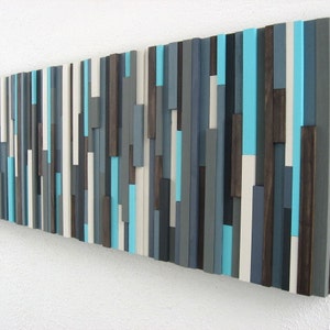 Pu&ograve; includere: Arte da parete astratto realizzato in legno con una variet&agrave; di tonalit&agrave; di blu, grigio e bianco. Il legno &egrave; disposto in uno schema verticale, creando un aspetto moderno e minimalista.