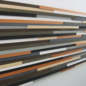 May include: A wall art piece made of wood planks in various shades of brown, gray, white, and orange. The planks are arranged in a staggered pattern, creating a modern and abstract design.