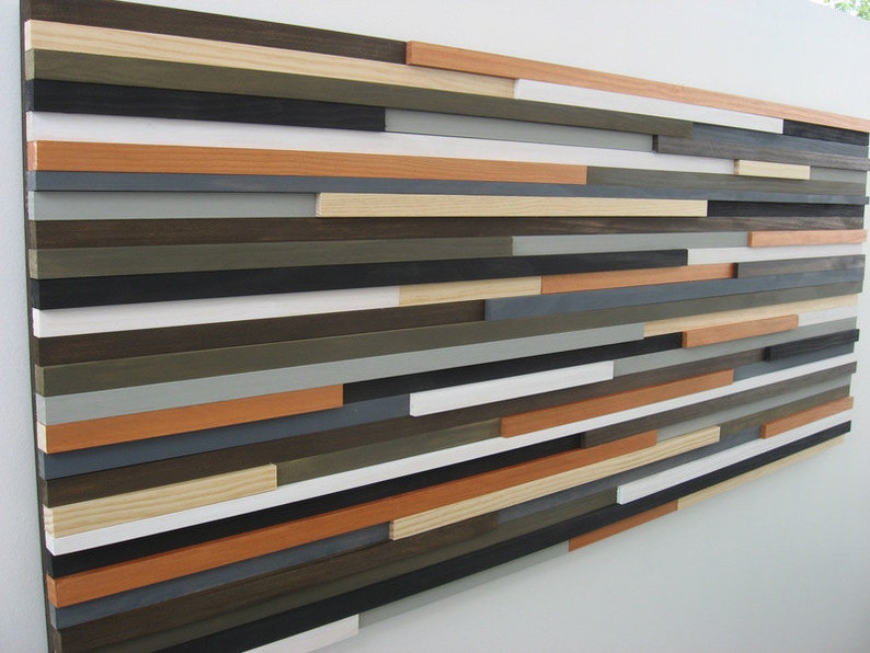 May include: A wall art piece made of wood planks in various shades of brown, gray, white, and orange. The planks are arranged in a staggered pattern, creating a modern and abstract design.