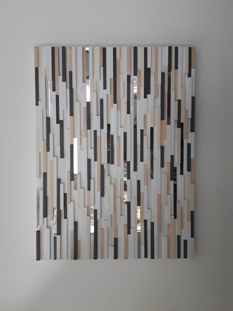 May include: A rectangular mirror with a unique design. The mirror is made up of many small, rectangular pieces of wood in various shades of brown, white, and black. The pieces are arranged in a random pattern, creating a modern and abstract look.