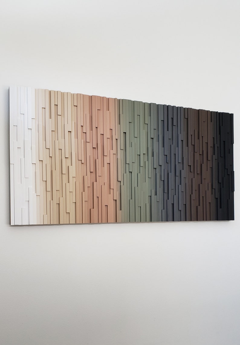 May include: A wall art piece made of wood with a gradient of colors from white to black. The wood is arranged in a vertical pattern, creating a textured look.