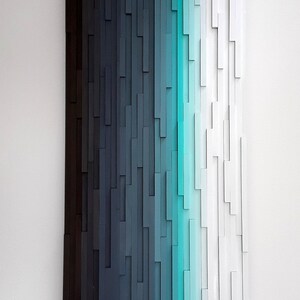 May include: Abstract wall art made of wood with a gradient of colors from black to white, with a turquoise blue stripe in the center.