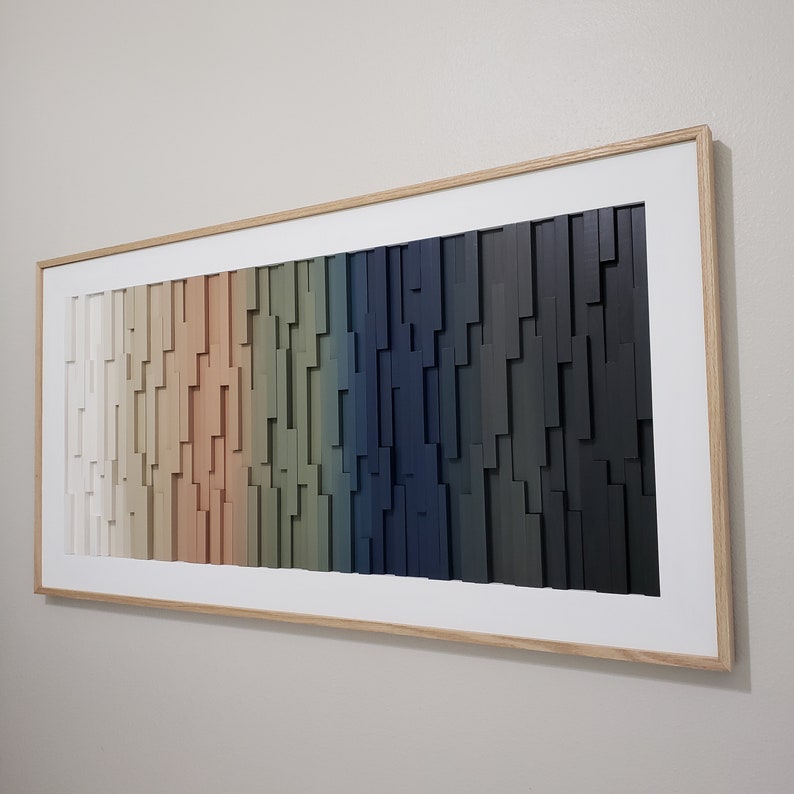 May include: A framed abstract wall art piece with a gradient of colors, starting with white and transitioning to dark blue. The art is made of wood and has a geometric pattern.