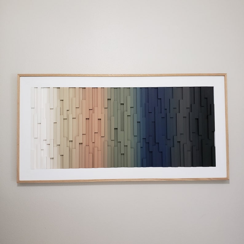 May include: A framed wood wall art piece with a gradient of colors from white to black. The wood is arranged in a vertical pattern, creating a textured effect.