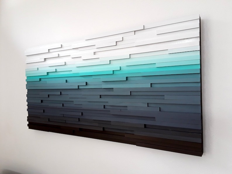 May include: Abstract wall art made of wood with a gradient of colors from white to dark gray, with a turquoise blue section in the middle.