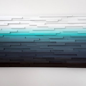 May include: Abstract wall art made of wood with a gradient of colors from white to black, with a turquoise blue band in the middle.