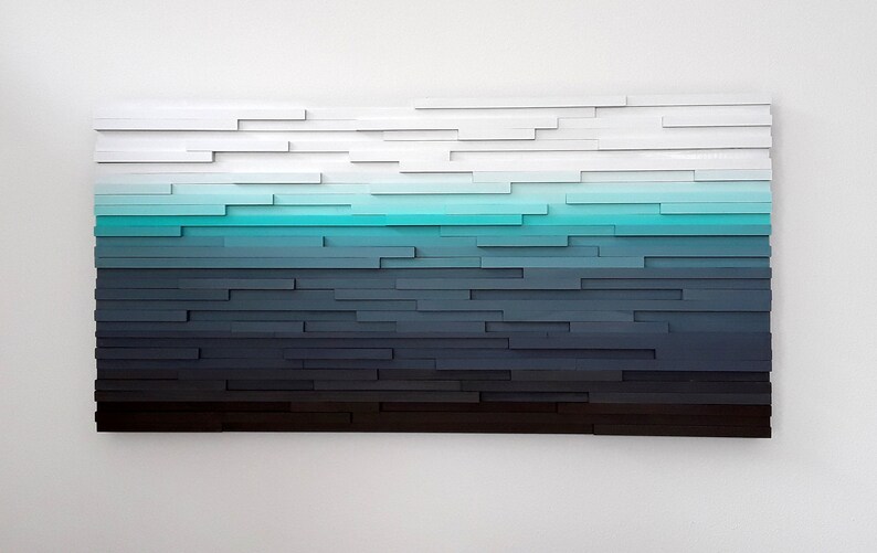 May include: Abstract wall art made of wood with a gradient of colors from white to black, with a turquoise blue band in the middle.