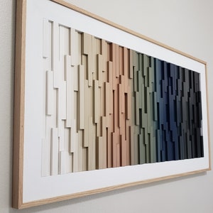 May include: A framed wood wall art piece with a gradient of colors from white to dark blue. The wood pieces are arranged in a staggered pattern, creating a textured effect.