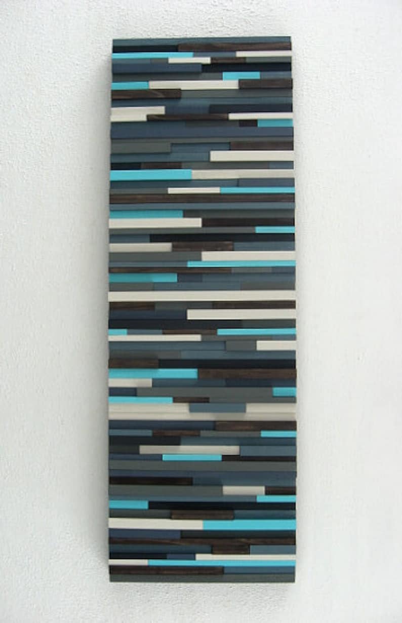 Pu&ograve; includere: Arte murale astratto realizzato con listelli di legno in tonalit&agrave; di blu, grigio e bianco. I listelli sono disposti in un motivo orizzontale, creando un design moderno e minimalista.