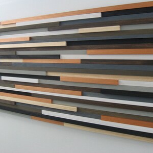 May include: A wall art piece made of various wood planks in shades of brown, gray, white, and orange. The planks are arranged in a horizontal pattern, creating a modern and abstract design.