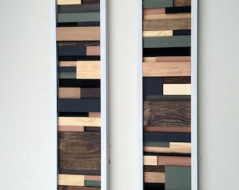 May include: Two framed wood wall art pieces with a geometric design. The pieces are made of various shades of brown, black, and green wood. The frames are white.