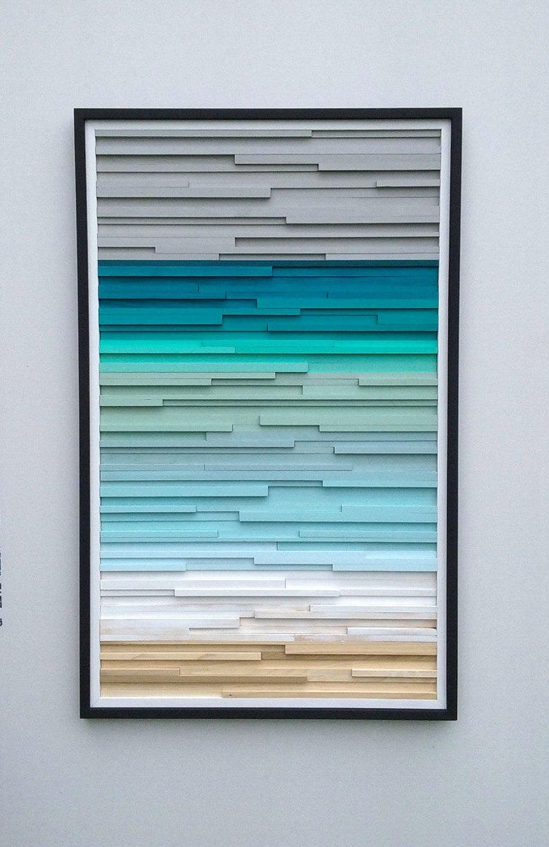 May include: A framed abstract art piece with a gradient of colors, starting with gray at the top, transitioning to teal, then light blue, white, and ending with a light brown at the bottom.