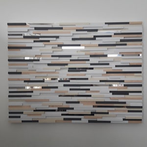 May include: A wall art piece made of wood and mirror tiles. The tiles are arranged in a random pattern, creating a modern and abstract design. The colors are black, white, and beige.