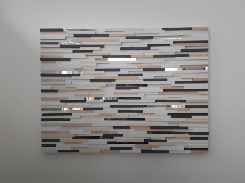 May include: A wall art piece made of wood and mirror tiles. The tiles are arranged in a random pattern, creating a modern and abstract design. The colors are black, white, and beige.