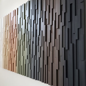 May include: A wall art piece made of wood with a gradient of colors from white to black. The wood is arranged in a staggered pattern, creating a textured surface.