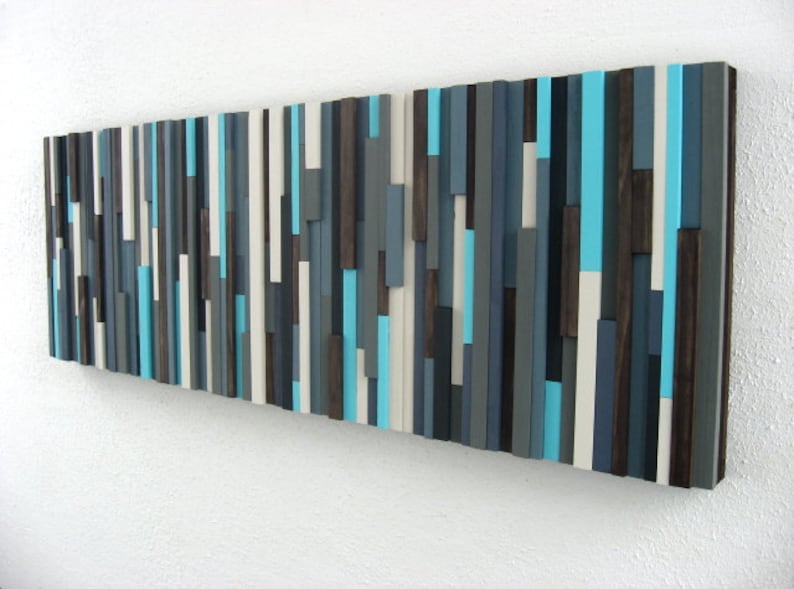 Pu&ograve; includere: Arte da parete astratto realizzato con listelli di legno in tonalit&agrave; di grigio, bianco e turchese. I listelli sono disposti in un motivo verticale, creando un design moderno e minimalista.