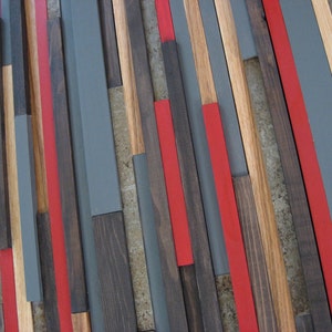May include: A wall art piece made of wood strips in various shades of brown, gray, and red. The strips are arranged in a geometric pattern, creating a modern and abstract design.