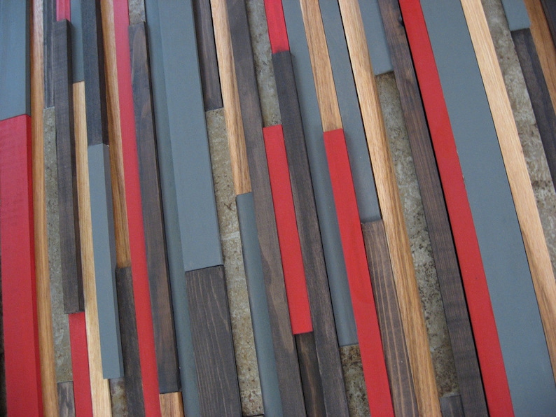 May include: A wall art piece made of wood strips in various shades of brown, gray, and red. The strips are arranged in a geometric pattern, creating a modern and abstract design.