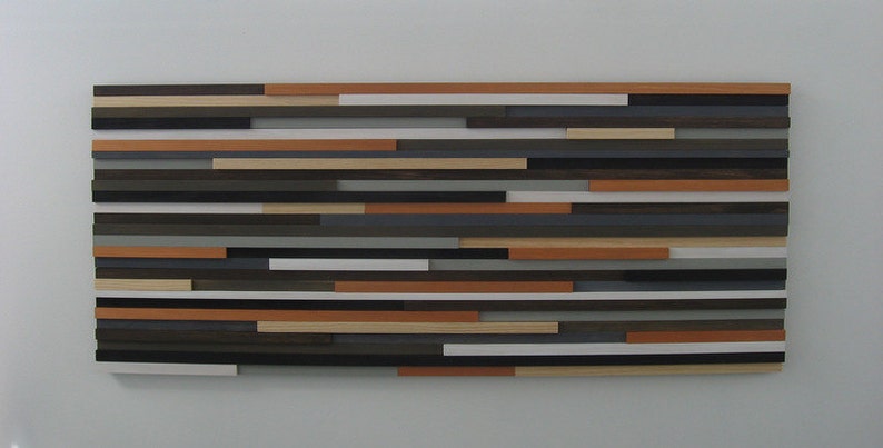 May include: A wall art piece made of wood slats in various shades of brown, gray, and white. The slats are arranged in a horizontal pattern, creating a modern and abstract design.