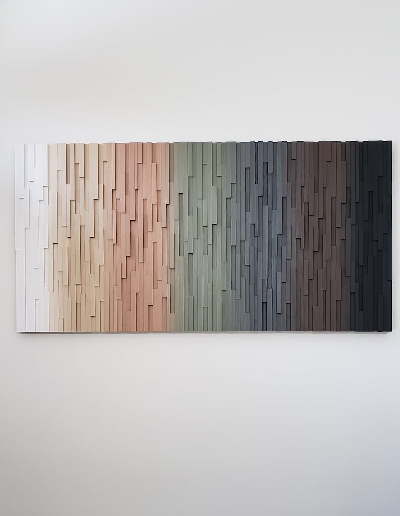 May include: A wall art piece made of wood with a gradient of colors from white to black. The wood is arranged in a vertical pattern, creating a textured effect.