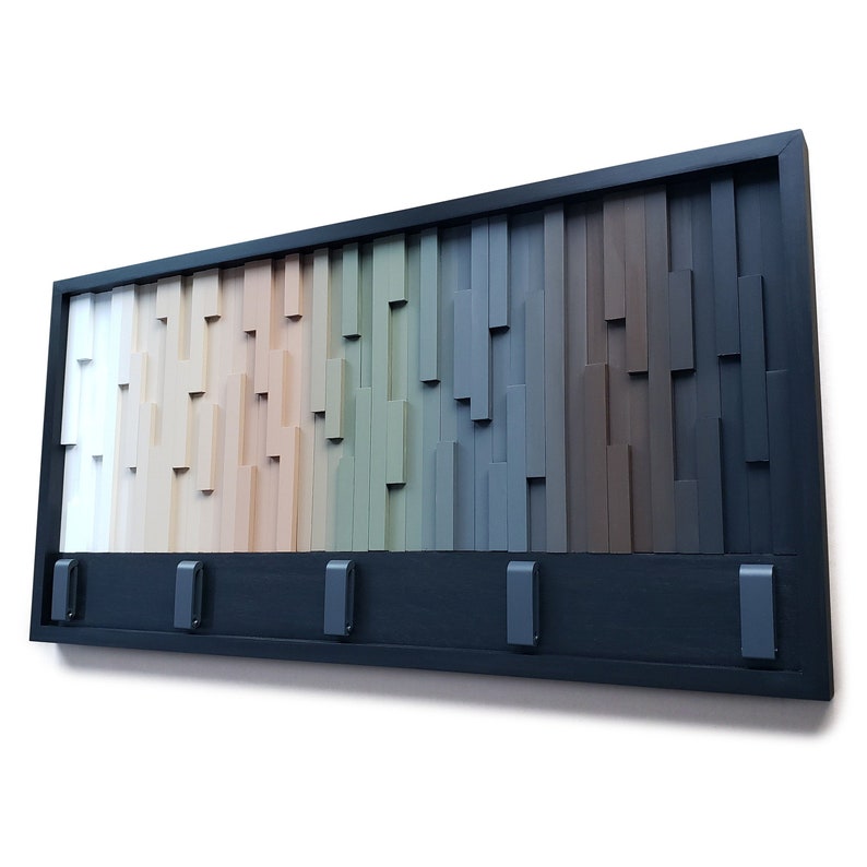 May include: A wooden wall-mounted coat rack with five hooks. The rack is made of wood slats in various shades of brown, beige, green, and gray. The hooks are black metal.