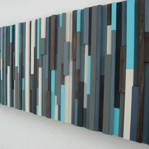 Pu&ograve; includere: Arte da parete astratto realizzato con assi di legno in tonalit&agrave; di grigio, bianco e turchese.
