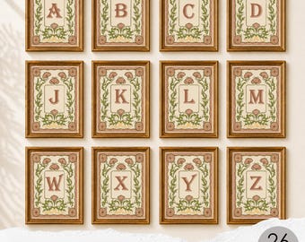 Può includere: Una collezione di dodici stampe rettangolari incorniciate con le lettere dell'alfabeto dalla A alla Z. Ogni stampa mostra una lettera centrale in carattere serif circondata da illustrazioni botaniche verdi e motivi floreali su sfondo crema.