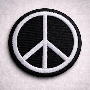 Könnte beinhalten: Ein runder, schwarzer Aufnäher mit einem weißen, gestickten Friedenssymbol. Das Friedenszeichen ist mittig auf dem Aufnäher platziert, mit einem dicken weißen Rand. Der Aufnäher ist wahrscheinlich für Kleidung oder Accessoires.