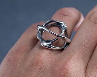 Anillo escultórico abierto de plata de ley sin tratar, joyería orgánica brutalista de gran impacto, anillo de plata moderno y abstracto, diseño arquitectónico industrial.