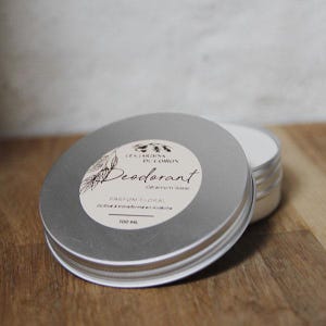 Peut inclure: Une boîte en étain argentée avec une étiquette blanche qui indique "Les Jardins du Coiron Déodorant Géranium Rosat Parfum Floral 100 ml".