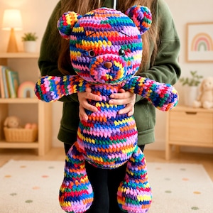 May include: A plush teddy bear crafted from multicolored yarn featuring a vibrant mix of blue, pink, yellow, green, and purple hues. The stuffed animal has a round head, two small ears, a brown nose, and black eyes, with a textured crochet pattern.