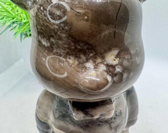 May include: A brown and white stone bear figurine with a detailed, textured surface. The bear has a round head with large ears and a small, round nose.