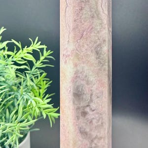 May include: A pink and white crystal point with a hexagonal base. The crystal has a marbled appearance with swirls of pink and white.