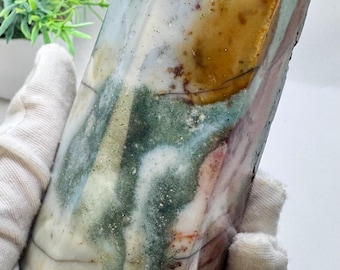 May include: A multi-colored crystal point with shades of white, green, yellow, and red. The crystal is polished and has a smooth, glassy surface.