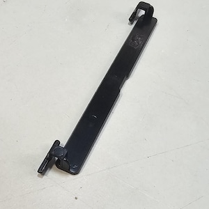 Könnte beinhalten: Schwarzer Kabelbinder aus Kunststoff mit einem kleinen, runden, schwarzen Knopf an einem Ende und einem Haken am anderen Ende.