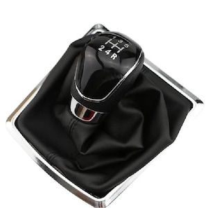 Könnte beinhalten: Schwarzer Lederschalthebelmanschette mit Chromzierleiste und schwarzem Schalthebelknauf mit silberner Beschriftung, die die Gangpositionen 1, 2, 4, R, 5, 6 anzeigt.