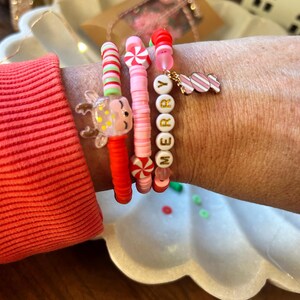 Puede incluir: Cuatro pulseras de cuentas de colores con un dije de bast&oacute;n de caramelo y un dije de reno. Las pulseras deletrean "Merry" en letras doradas.