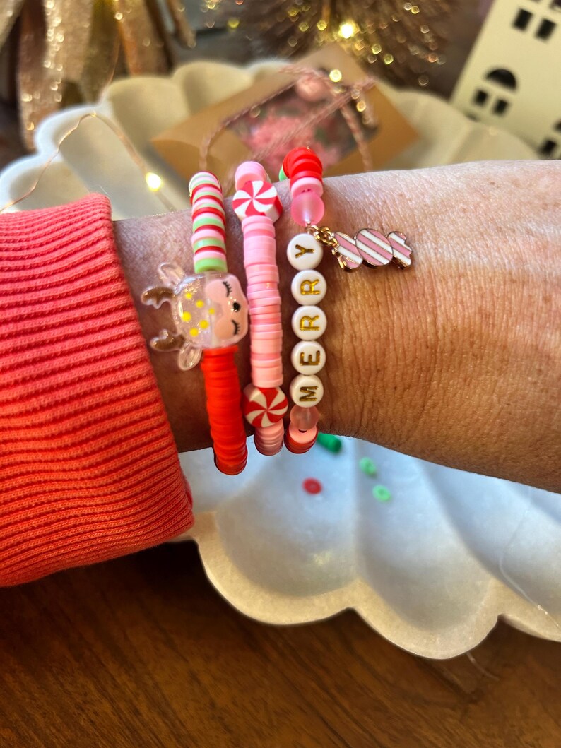 Puede incluir: Cuatro pulseras de cuentas de colores con un dije de bast&oacute;n de caramelo y un dije de reno. Las pulseras deletrean "Merry" en letras doradas.