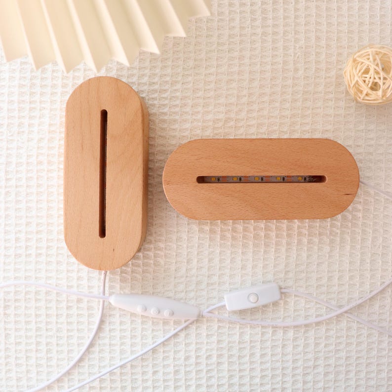 May include: Two wooden LED light bases with a white cord and switch. One base is vertical with a long slot, the other is horizontal with a row of lights. The bases are oval-shaped and made of light-colored wood.