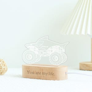 May include: A shark-shaped monster truck night light with the name "Grace" etched on the side. The light sits on a wooden base with the text "You are my life." The light is connected to a white cord.