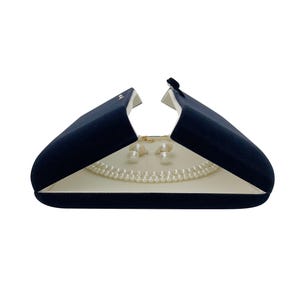 May include: A navy blue velvet jewellery box with a white interior, open to reveal a pearl necklace and pearl earrings.